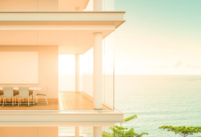 Vista de un balcón con mesa y puesta de sol en el mar